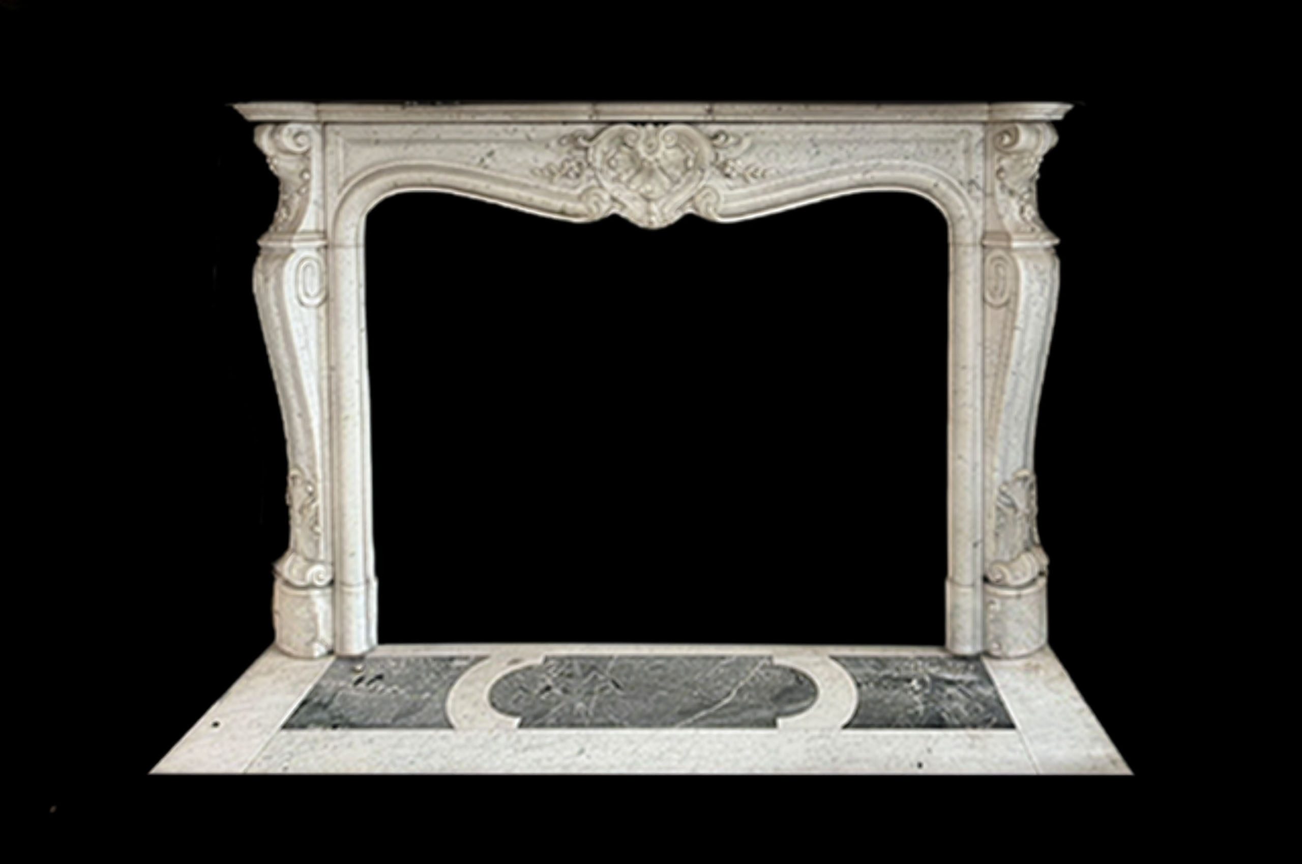 A late 19th-century Louis XV Revival fireplace and hearth carved in Carrara marble, featuring a serpentine frieze and central cartouche. 